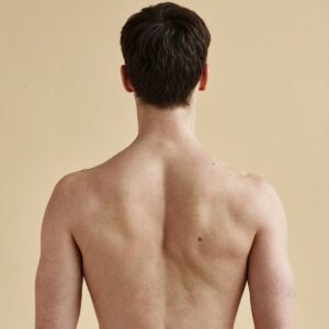 Vue de dos d'un homme torse nu montrant une peau lisse et sans poils sur tout le dos, les épaules et la nuque