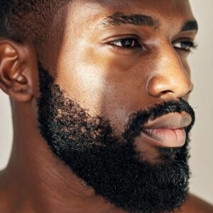 Profil d'un homme à la peau noire arborant une barbe avec des poils incarnés